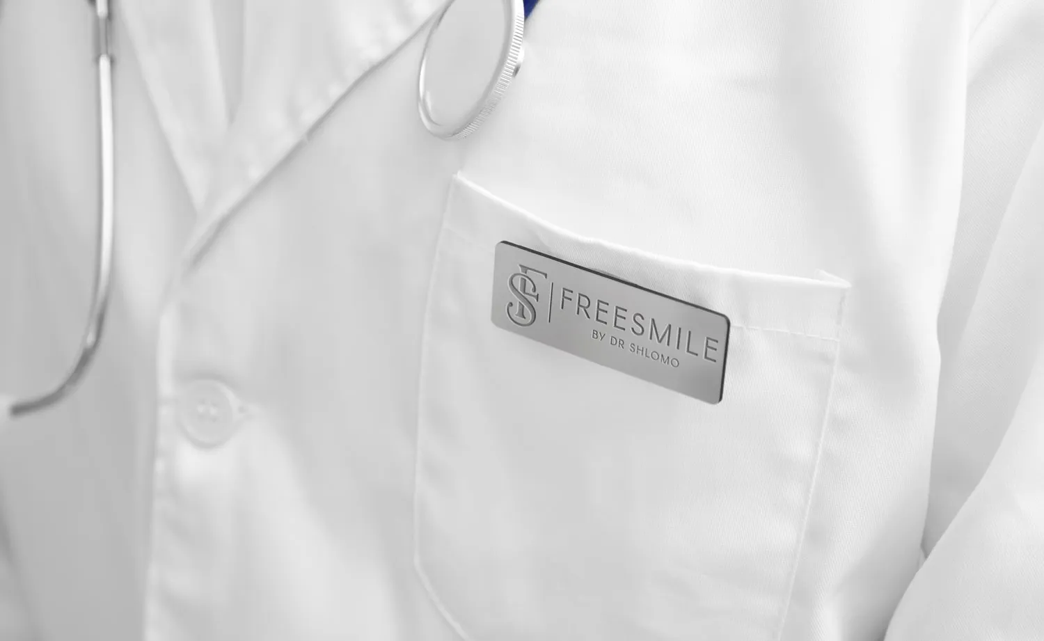 המיתוג של FreeSmile: תג מתכת עם הלוגו על חלוק רופא